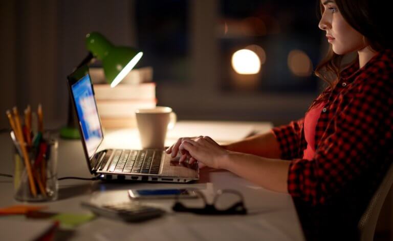 student or woman typing on laptop at night home
